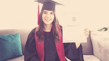 woman holding a college degree certificate in her hands with a black cap and gown and red robe