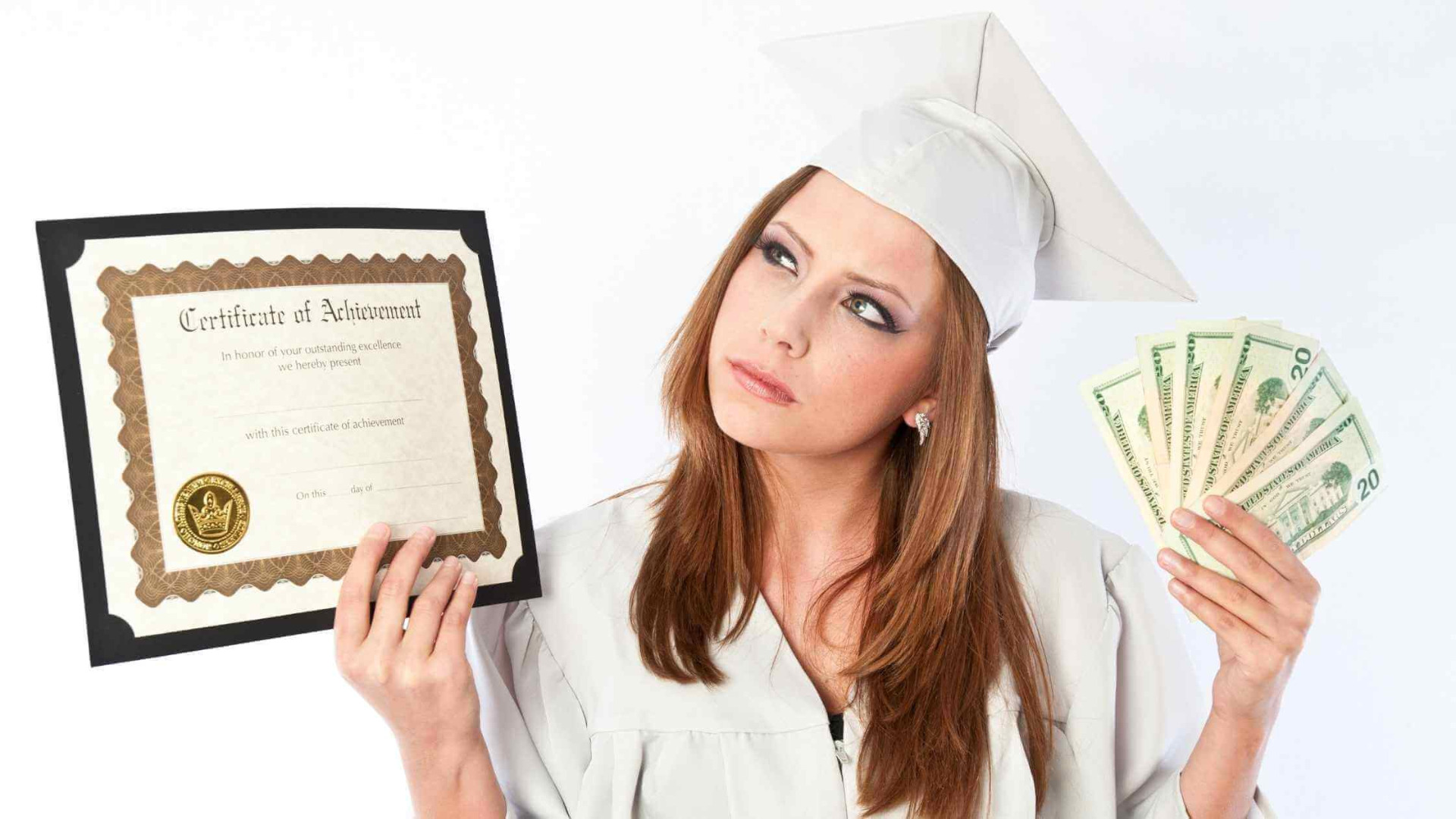 beautiful ginger graduate in white cap and gown holding her certificate and a pile of cash showing the true cost of a degree