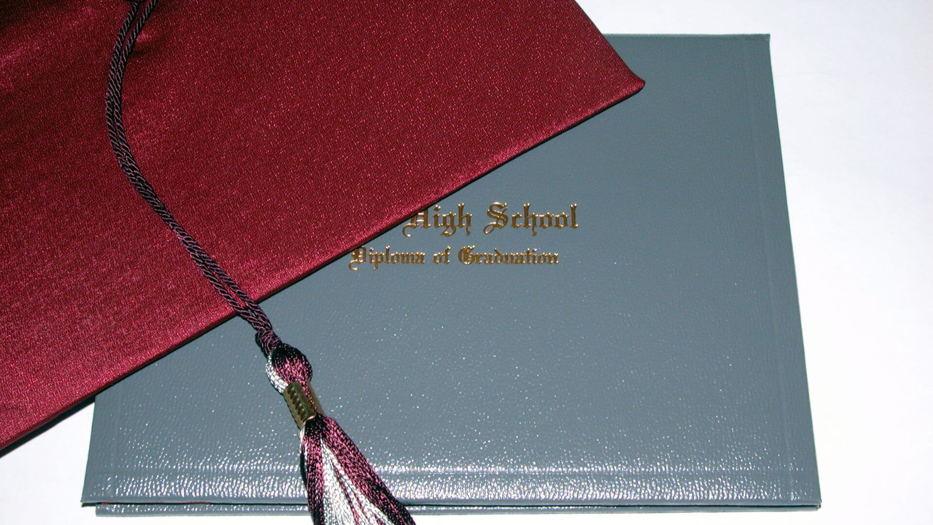 red graduation cap over top of a cover for a diploma from high school