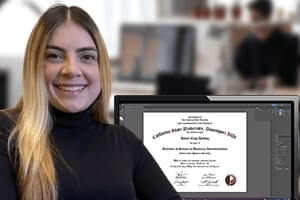 happy female designer sitting in front of her monitor with a diploma on the screen